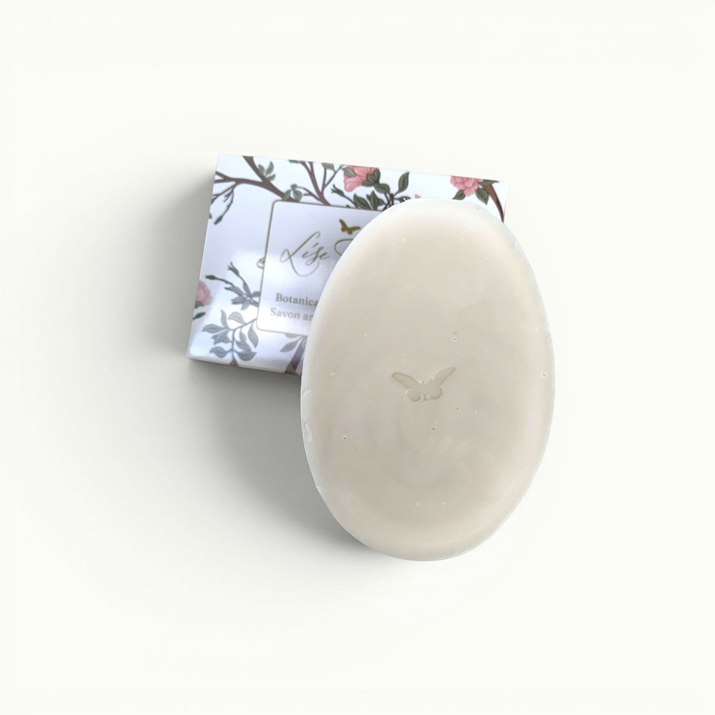 Lise Fiola Creations artisanal oval soap bar with a butterfly imprint, featuring botanical packaging.