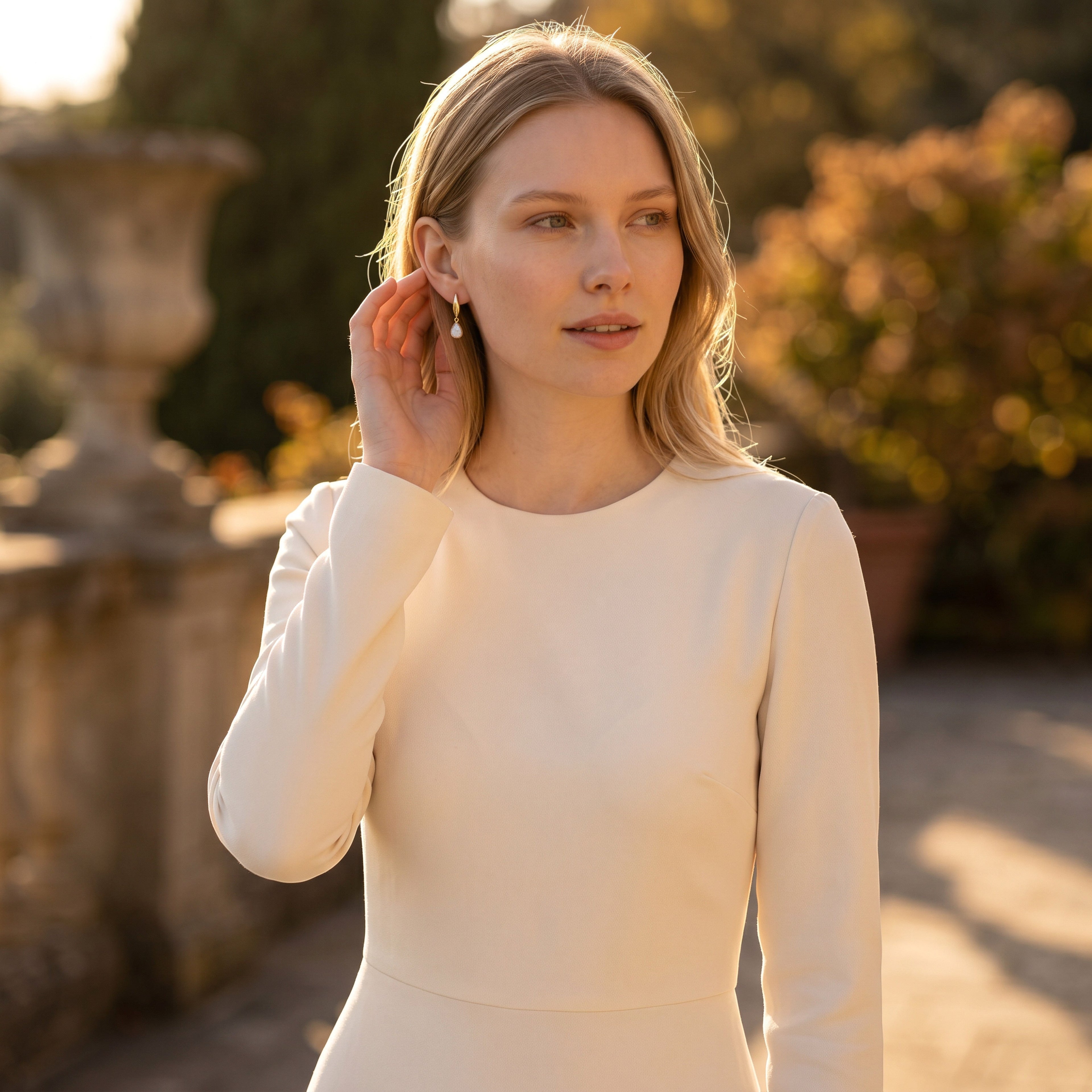 Lise Fiola Creations Dot Drop earrings in marbled beige and gold worn by a woman in a cream dress outdoors.