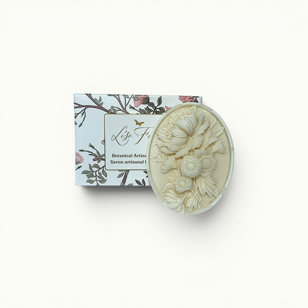 Lise Fiola Creations artisanal soap bar with intricate floral relief design next to its botanical-themed packaging.