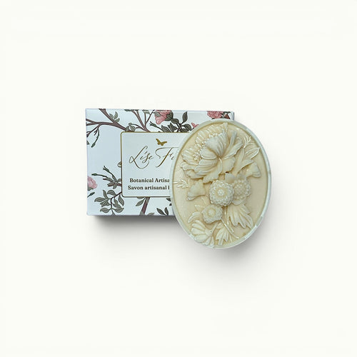 Lise Fiola Creations artisanal soap bar with intricate floral relief design next to its botanical-themed packaging.