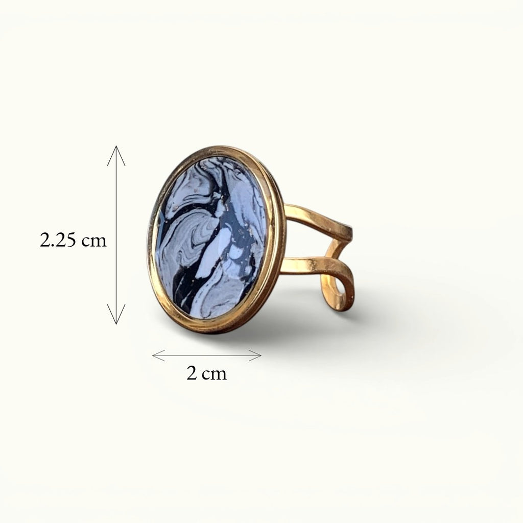 Lise Fiola Creations oval ring with a black, grey, and white marbled polymer clay inlay on an adjustable gold band.