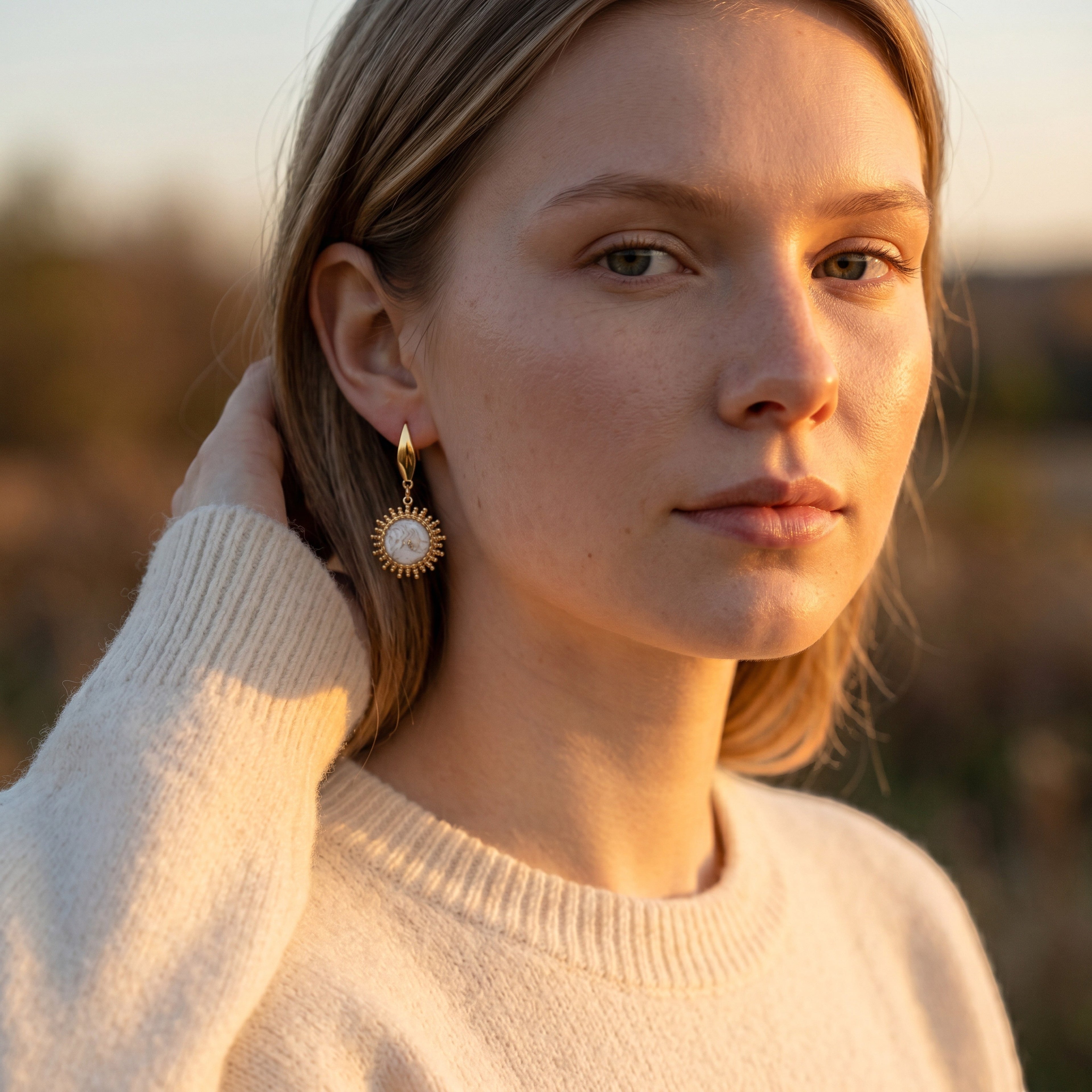 Model wearing Lise Fiola Creations Sunshine earrings featuring marbled polymer clay and 14k gold-plated sunburst detail.