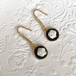 Lise Fiola Creations handmade drop earrings featuring white polymer clay rose details on black discs with gold-plated hooks.